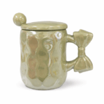 Lichtgroene porseleinen mok met deksel, lepel en strikvormig handvat op witte achtergrond